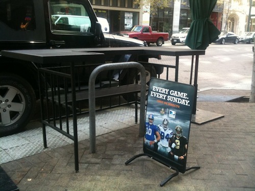 ABOVE: Public bike rack hidden behind cafe tables & advertising