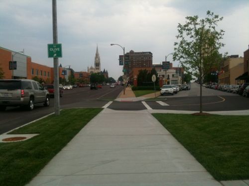 The pedestrian is allowed to continue on a straight path with ramps, detectable warnings, and crosswalk that reinforce each other.   