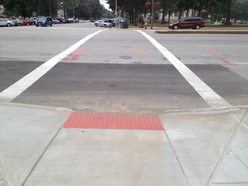 SLU at least did directional ramps in front of their new law school building, but the crossing distances are excessive. Bulbs at the ends of the parking lanes will reduce crossing widths.