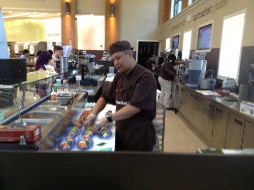 The chef prepares sushi while others get a beverage from the juice bar, frozen yogurt is in the background left 