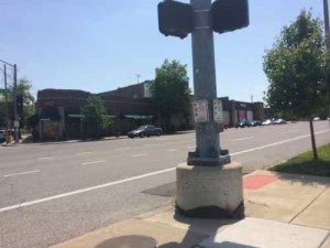 An incomplete street: The ramp is on the other side of the traffic signal base, opposite of the button. No crosswalk.