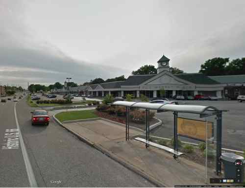 Google's Street View in March 2014 showed a spot where I could access the parking lot from the bus stop, no designated route. Click image for map link