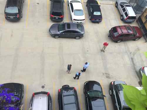 Police officers talking to a person whose car is blocked and a person who blocked. 