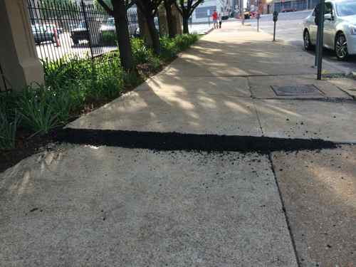 Less than a week later a little asphalt was now placed at various points to make the sidewalk less hazardous, but the rough utility covers remained for months. 