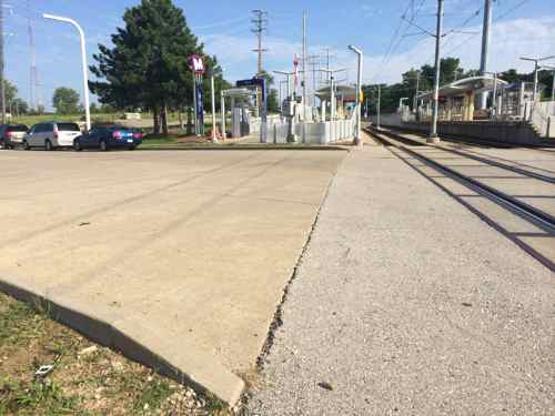 The civil engineer responsible for Sunnen Dr didn't plan a way for pedestrians to cross it, the only option is to squeeze between the crossing gate and track. 