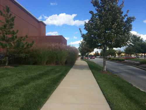 View looking east along the main east-west pedestrian route, which is parallel to the main east-west auto route, the building on the left contains several storefronts and a bank is just beyond that. 