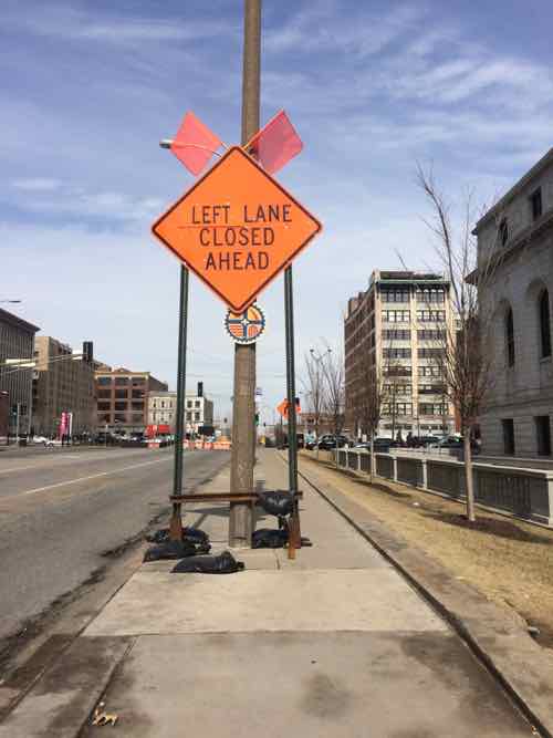 This is the 2nd sign on the sidewalk, a bus stop is just beyond