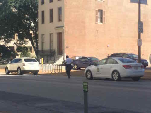 Parking enforcement officer carrying a big blue bag to the Ford Edge, August 2015