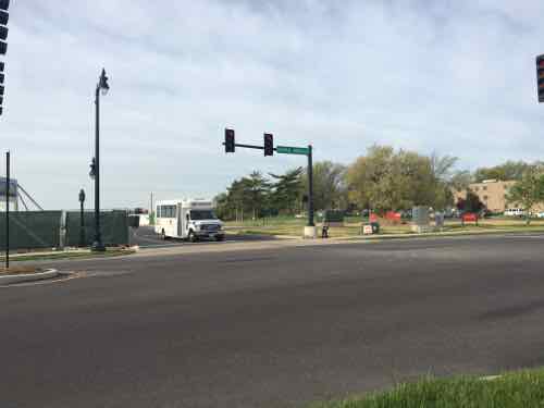 Diagonally across the intersection I noticed a child waiting for the walk signal to cross the side street